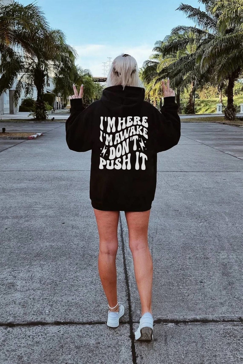 May include: Black hooded sweatshirt with white text that reads "I'm here I'm awake Don't push it" with lightning bolt symbols on either side of the word "Don't".
