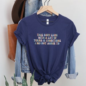 May include: Navy blue t-shirt with a colorful graphic that reads "This body came with a lot of terms & conditions I did not agree to".