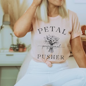 May include: A pink t-shirt with the text "PETAL professional PUSHER" and a black and white illustration of a bouquet of flowers.