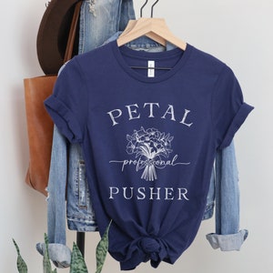 May include: A navy blue t-shirt with white text that reads "PETAL professional PUSHER" and a white floral graphic.