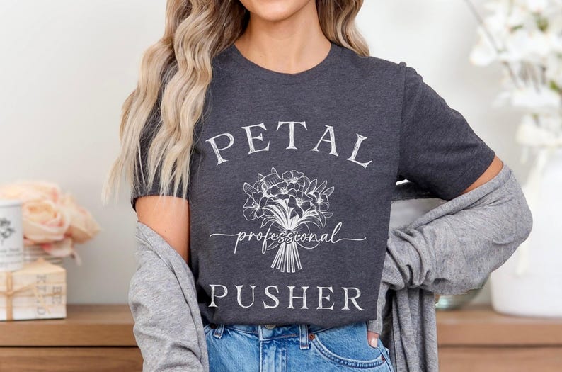 May include: A dark gray t-shirt with white text that reads "PETAL professional PUSHER" and a white floral design.