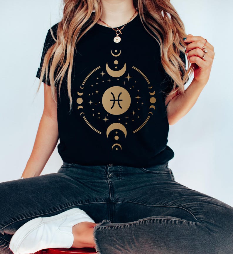 May include: Black t-shirt with a gold Pisces zodiac symbol surrounded by a circle of moons and stars.