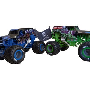 May include: Two toy monster trucks, one blue and one green, are displayed. The blue truck has a pirate flag and the text "Grave Digger" on the green truck. Both have large tires with the text "BKT".