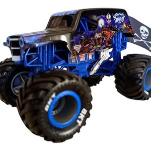 May include: A toy monster truck with a black and blue design. The truck has large black tires with blue accents and the text "BKT". The truck features a skull and crossbones flag and the text "Grave Digger".