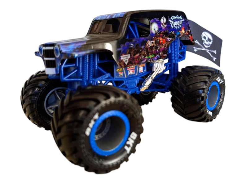 May include: A toy monster truck with a black and blue design. The truck has large black tires with blue accents and the text "BKT". The truck features a skull and crossbones flag and the text "Grave Digger".