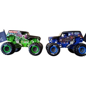 May include: Two toy monster trucks, one green and one blue, with large tires. The green truck has "Grave Digger" on the roof and a skull and crossbones flag. The blue truck has "Monster Jam" on the roof and a skull and crossbones flag.