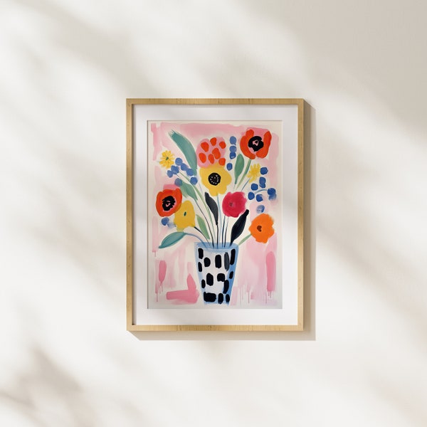 Può includere: Una stampa incorniciata di un dipinto ad acquerello con un mazzo di fiori colorati in un vaso con motivo bianco e nero. I fiori sono rossi, arancioni, gialli, blu e verdi. Lo sfondo è rosa chiaro.