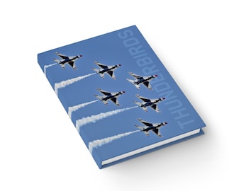 May include: A blue notebook with a photo of the Thunderbirds air show team flying in formation. The text "THUNDERBIRDS" is printed vertically on the cover.