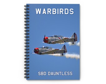 May include: Spiral-bound notebook featuring two vintage warplanes against a blue sky. The notebook cover displays the text "WARBIRDS" at the top and "SBD DAUNTLESS" at the bottom. The planes are silver with red accents and American flag details.