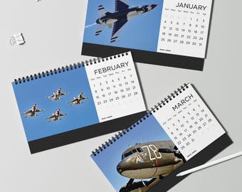 May include: Desktop calendars featuring aviation themes. The calendars display images of aircraft, including fighter jets and a vintage plane, with monthly date grids. The January calendar shows a jet in flight, while February features a formation of jets.