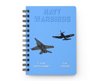 May include: A blue notebook with a spiral binding. The cover features the text "NAVY WARBIRDS" in white with a 3D effect. Two images of fighter jets are shown: a blue and white F/A-18F Super Hornet and a black F4U Corsair. The text "F/A-18F SUPER HORNET" and "F4U CORSAIR" are printed below the jets.