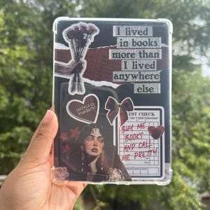 Puede incluir: Una funda protectora transparente para tableta, adornada con pegatinas y texto. El dise&ntilde;o incluye un ramo de rosas rojas, un coraz&oacute;n con la frase "Hopeless Romantic" y un retrato de mujer. El texto dice "I lived in books more than I lived anywhere else."