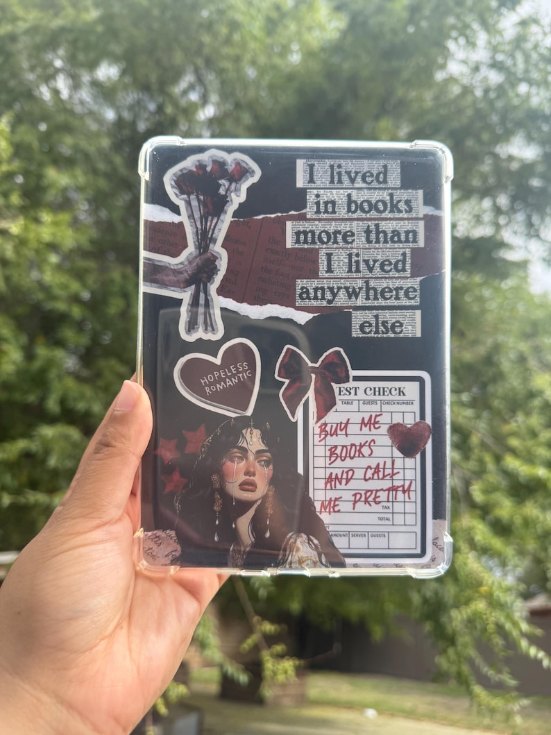 Puede incluir: Una funda protectora transparente para tableta, adornada con pegatinas y texto. El dise&ntilde;o incluye un ramo de rosas rojas, un coraz&oacute;n con la frase "Hopeless Romantic" y un retrato de mujer. El texto dice "I lived in books more than I lived anywhere else."