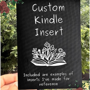 May include: A black rectangular Kindle insert with white text that reads "Custom Kindle Insert." Below the text is a white floral design above the text "Included are examples of inserts I've made for reference."