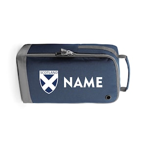 May include: A navy blue shoe bag with a grey zipper and a grey trim. The bag has a white Scottish flag logo and the word "SCOTLAND" above it. The bag also has the word "NAME" printed in white.