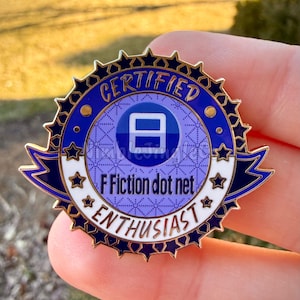 Op de afbeelding: Een ronde emaille pin in blauw en goud met de tekst "CERTIFIED ENTHUSIAST" en "F Fiction dot net". De pin heeft een sterrenpatroonrand en een centrale blauwe cirkel met een wit symbool.