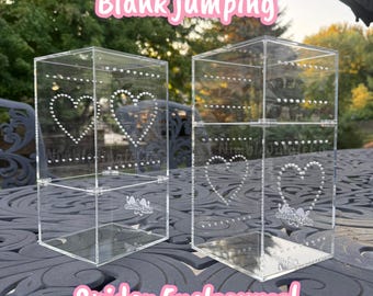 以下が含まれることがあります： ハートのデザインと「Blank jumping Spider Enclosures！」の文字が入った、2つの透明なアクリル製エンクロージャー。エンクロージャーは長方形で、ヒンジ付きのドアと内部に小さな棚があります。