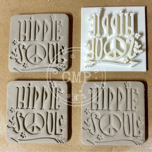 May include: Four square ceramic tiles with the words "Hippie Soul" and a peace sign in raised lettering. The tiles are in two different colors, white and brown.
