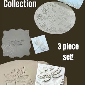 May include: A set of three white polymer clay stamps featuring dragonfly designs. The stamps are in various sizes and shapes, including a rolling pin, a square, and a rectangle. The stamps are part of a "Dragonfly Collection" and are labeled "3 piece set!"