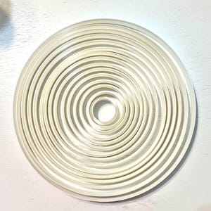 May include: A set of 18 white circular cookie cutters of varying sizes, arranged in a concentric pattern.