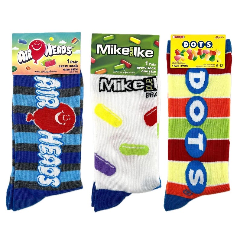 May include: Three pairs of crew socks featuring colorful candy designs. The socks are blue, white, and yellow with the Air Heads, Mike and Ike, and Dots candy logos.