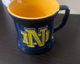 Taza de café NCAA Notre Dame Fighting Irish azul marino/amarilla con relieve 3D. En perfecto estado. ¡Genial!