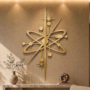 Op de afbeelding: Een goudkleurige, moderne atoom-starburst wanddecoratie uit het midden van de eeuw siert een beige muur. Het kunstwerk heeft starbursts, cirkels en lijnen. Een marmeren console, een beige fauteuil en potplanten maken de kamer compleet.