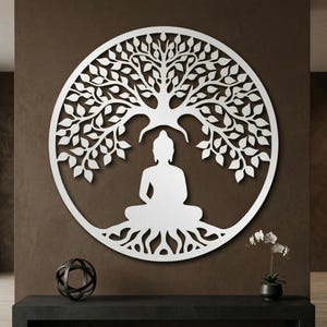 May include: White metal wall art featuring a seated Buddha under a tree within a circular frame. The design includes detailed leaves, roots, and a serene Buddha figure, suitable for meditation spaces or home decor.