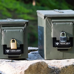May include: Two green metal ammo cans with latch locks. The smaller can has a brass padlock, and the larger can has a black padlock. Both padlocks have a black label that says "Latch Lock Ammo Can Security".