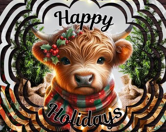 May include: A circular metal wind spinner featuring a Highland cow wearing a red and green plaid scarf and holly berries on its head. The text Happy Holidays is printed in black script. The design includes evergreen trees and a snowy base.
