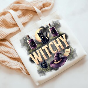 May include: A white canvas tote bag featuring a graphic print with the word WITCHY in large beige letters. The design includes two black cats, a crescent moon, two purple potion bottles, a witch hat, and an open book amidst dark smoke.