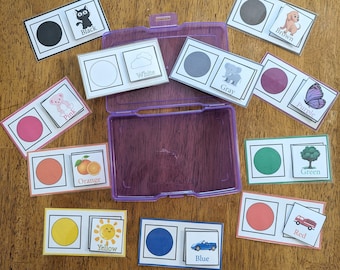 May include: A set of colour matching cards with a colour circle and a picture on each card. The colours include black, white, grey, pink, orange, yellow, blue, green, red and purple.