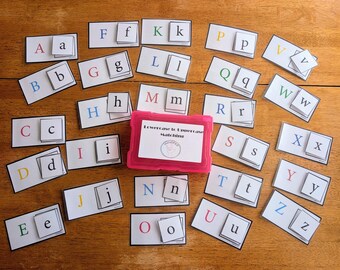 May include: A set of alphabet matching cards featuring uppercase and lowercase letters in various colours, arranged around a bright pink plastic storage box. The box lid displays the text Lowercase to Uppercase Matching with a circular logo.