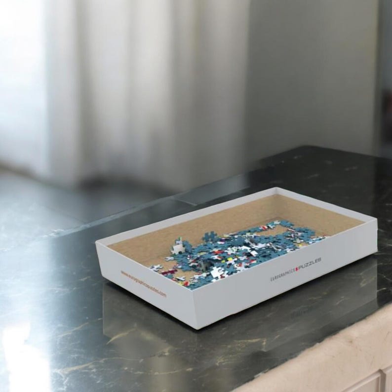 Peut inclure: Un puzzle de 1000 pièces représentant les drapeaux du monde. La boîte du puzzle est bleue avec du texte blanc et une image du puzzle terminé. Le puzzle est fabriqué par Eurographics.