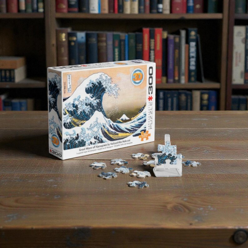 Peut inclure Un puzzle de 3000 pièces représentant une œuvre d'art japonaise célèbre, La Grande Vague de Kanagawa de Katsushika Hokusai. L'image représente une grande vague bleue qui se brise sur trois bateaux avec le mont Fuji en arrière-plan.
