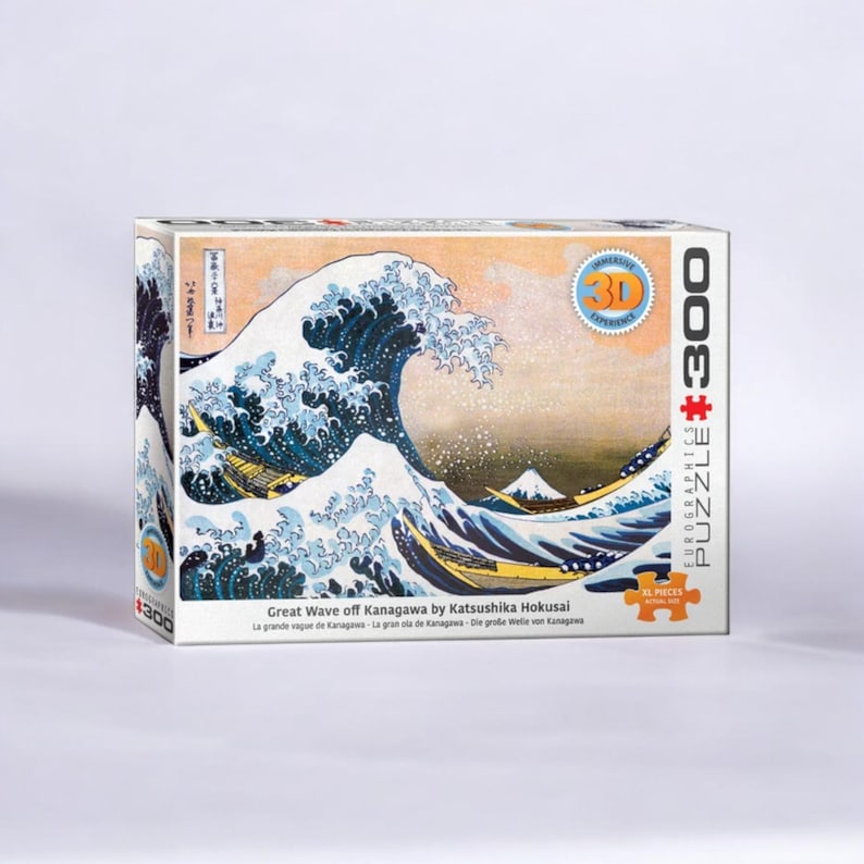 Peut inclure Un puzzle de 3000 pièces représentant une œuvre d'art japonaise célèbre, La Grande Vague de Kanagawa de Katsushika Hokusai. L'image représente une grande vague bleue qui se brise sur trois bateaux avec le mont Fuji en arrière-plan.