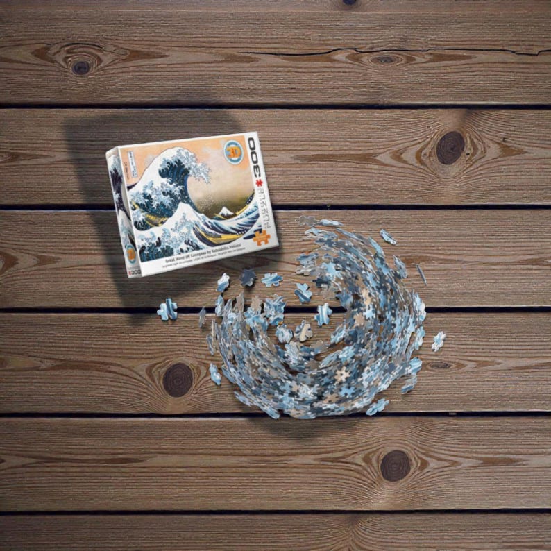 Peut inclure Un puzzle de 3000 pièces représentant une œuvre d'art japonaise célèbre, La Grande Vague de Kanagawa de Katsushika Hokusai. L'image représente une grande vague bleue qui se brise sur trois bateaux avec le mont Fuji en arrière-plan.