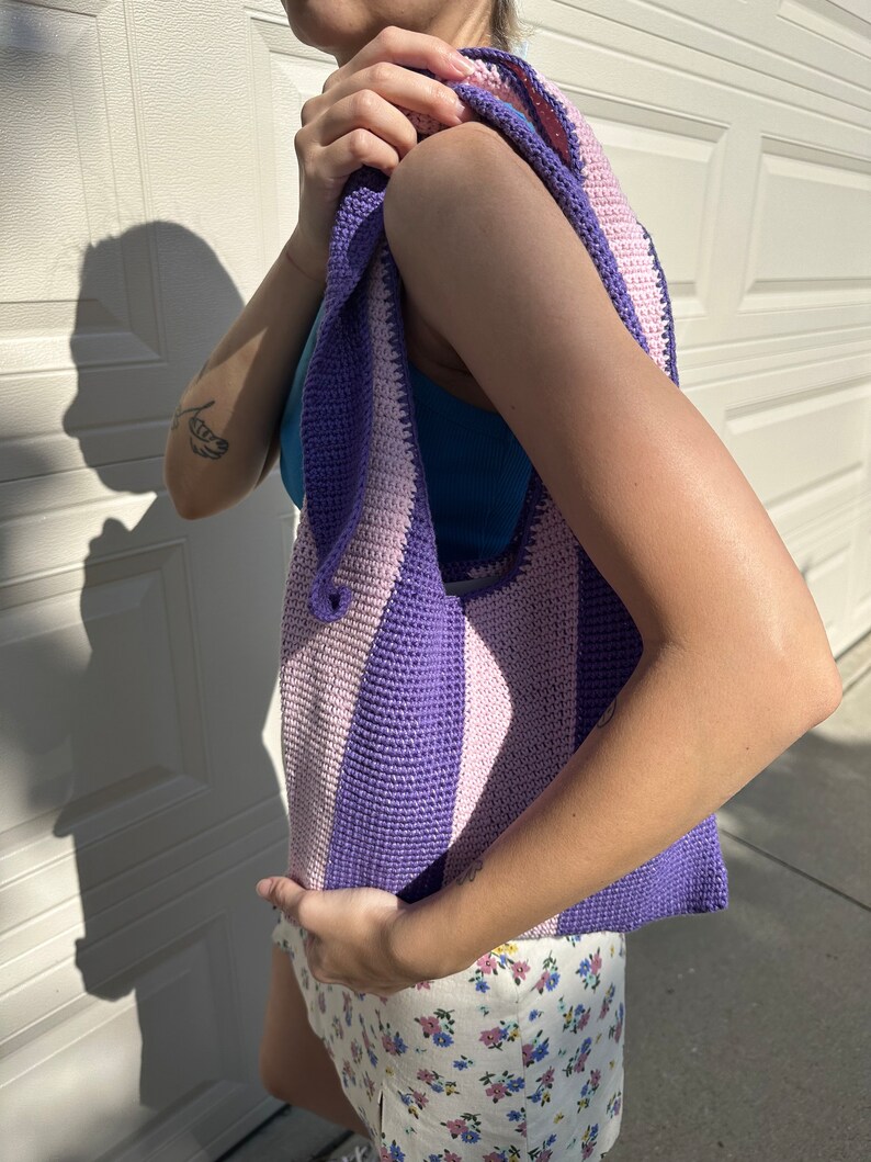 May include: A purple and pink striped crocheted tote bag with a wide strap.