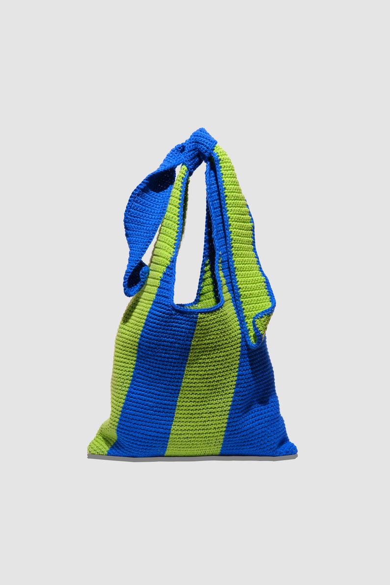 May include: A blue and green striped crocheted tote bag with a knotted handle.