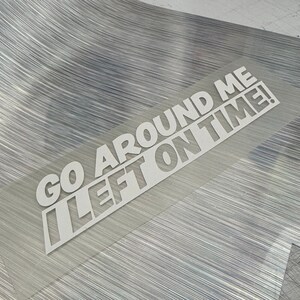 May include: White vinyl sticker with the text "Go Around Me I Left On Time!" on a silver background.