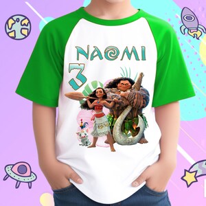 K&ouml;nnte beinhalten: Wei&szlig;es und gr&uuml;nes Raglan-T-Shirt mit einem Moana- und Maui-Motiv. Das Shirt hat den Namen "Naomi" und die Nummer "3" auf der Vorderseite.