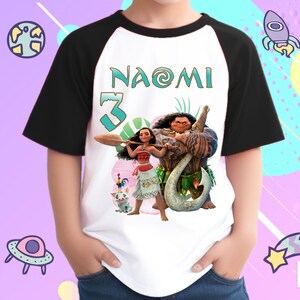 K&ouml;nnte beinhalten: Ein wei&szlig;es und schwarzes Baseball-T-Shirt mit einer bunten Grafik von Moana und Maui aus dem Disney-Film Moana. Das Shirt tr&auml;gt den Namen "Naomi" und die Nummer "3" auf der Vorderseite.