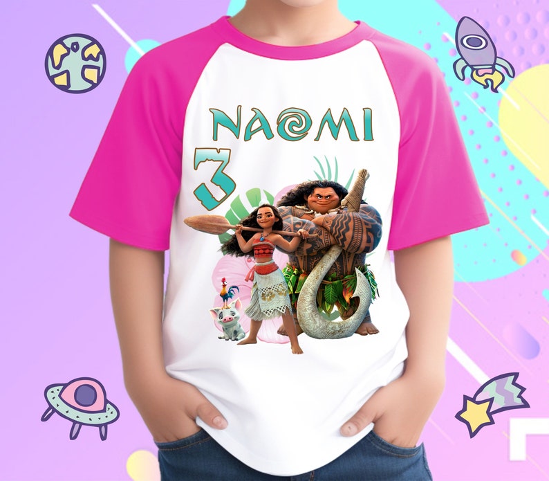 K&ouml;nnte beinhalten: Ein wei&szlig;es und pinkfarbenes Raglan-T-Shirt mit einem Moana- und Maui-Motiv. Das Shirt tr&auml;gt den Namen "NAOMI" und die Nummer "3" auf der Vorderseite.