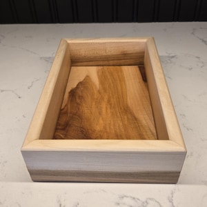 Peut inclure: Un plateau rectangulaire en bois avec une finition en bois brun clair. Le plateau a un bord surélevé et une surface lisse.