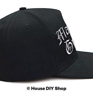 Peut inclure: Casquette de baseball noire avec texte brod&eacute; blanc. La casquette a une visi&egrave;re incurv&eacute;e et une couronne structur&eacute;e. Le texte sur la casquette se lit "MA TOWN" en police gothique. Un drapeau am&eacute;ricain est dans le coin sup&eacute;rieur gauche.