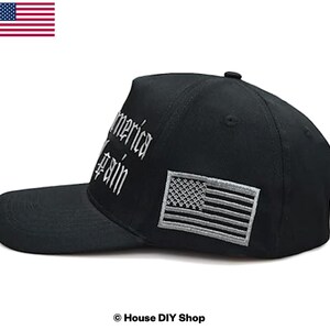 Peut inclure: Casquette de baseball noire avec le texte "America Again" brod&eacute; en blanc. Elle pr&eacute;sente un &eacute;cusson du drapeau am&eacute;ricain gris et blanc. La casquette a une visi&egrave;re incurv&eacute;e et une couronne structur&eacute;e.