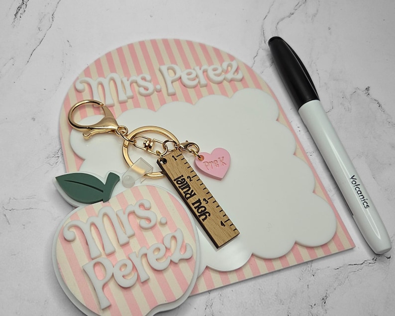 Reusable dry erase teacher desk board with scalloped whiteboard design and personalized teacher name. Classroom notepad used for reminders, daily notes, and lesson planning. Unique teacher appreciation gift idea, new teacher classroom decor piece, and back to school teacher desk accessory. Pair it with a matching apple keychain.