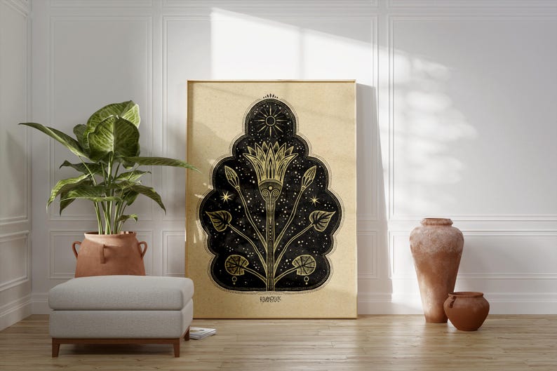 May include: A gold and black print of a stylized flower with a sun and stars on a beige background. The print is framed and hanging on a white wall.