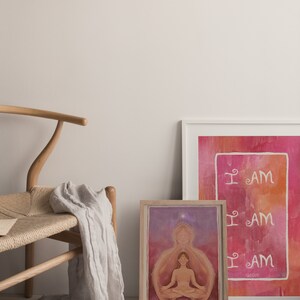 May include: Two framed art prints with a watercolor background. The print on the left features a woman meditating with a star above her head. The print on the right has the words "I AM" repeated three times in white.
