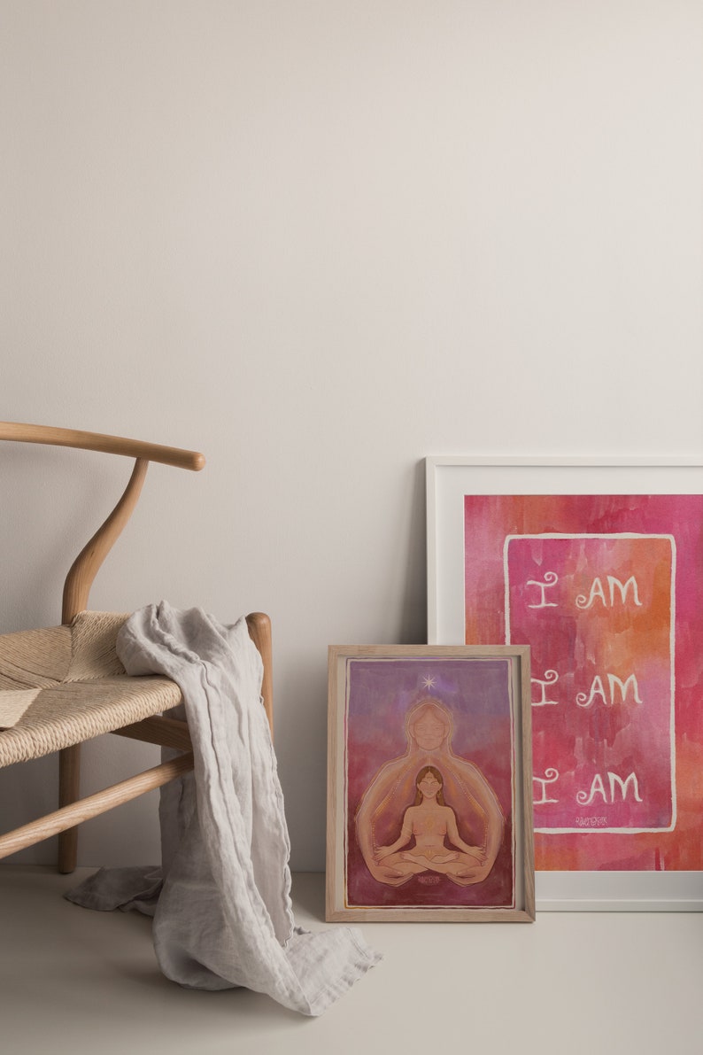 May include: Two framed art prints with a watercolor background. The print on the left features a woman meditating with a star above her head. The print on the right has the words "I AM" repeated three times in white.